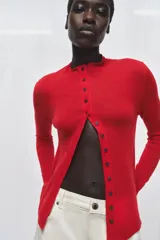 Chaqueta de punto extrafino color negro con cuello redondo y manga larga. Cierre frontal con hilera de botones pequeños.