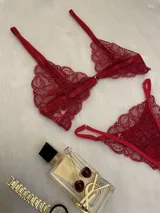 Conjunto de lencería de encaje rojo, compuesto por un bralette con cierre frontal y una tanga regulable con laterales finos.