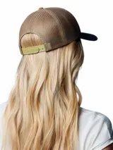 Gorro trucker Columbia Mesh Snap Back Hat, color marrón tostado con visera gris oscura y paneles traseros de malla. Cuenta con un parche gráfico redondo en el frente con diseño de montañas y cierre trasero ajustable.