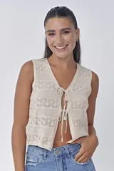 Chaleco de punto calado color crema con escote en V y cierre frontal con lazos.