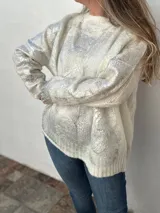 Buzo de tejido de punto grueso color beige con mangas largas y detalles dorados en el cuerpo.