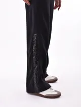 Pantalón de jogging negro de corte recto con cintura elástica ajustable con cordón y detalle de encaje en los laterales.