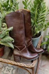 Bota de caña alta color marrón con textura símil reptil, taco cuadrado forrado en cuero y cierre lateral.