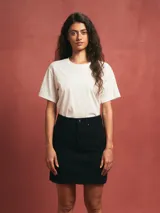 Falda corta de denim color negro, tiro alto, con dobladillo deshilachado y corte A.