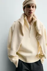 Jersey de punto color blanco con efecto pelo, cuello subido y cierre frontal de cremallera, de corte regular fit y manga larga con acabados en rib.