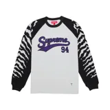 Camiseta de manga larga con diseño raglán, cuerpo blanco y mangas negras con estampado de rayas tipo tigre en blanco. Presenta el logo de Supreme y el número 94 en color violeta en el frente.