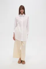 Camisa marrón holgada de algodón con cuello clásico, cierre frontal con botones y mangas largas con puños abotonados.