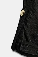 Blusa negra de cuello solapa y manga corta, con bolsillos con solapa en el pecho, bajo elástico y cierre frontal con botones.