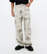 Pantalón de sarga de algodón con corte super baggy, tiro bajo y piernas ultra amplias. Presenta un estampado integral con efecto marmorizado o dirty, bolsillos utilitarios laterales, bolsillos frontales y traseros, cintura con pasantes y cierre frontal con botón y cremallera.