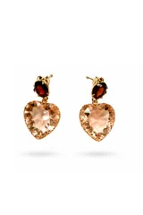 Caravanas colgantes con diseño de corazón facetado en tono rosado, con un detalle superior de piedra ovalada en color rojo oscuro. Cuentan con cierre de perno y son de diseño liviano.