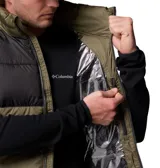 Chaleco acolchado Columbia, modelo Pike Lake II, con diseño bicolor en negro y verde militar. Cuenta con cierre frontal completo, cuello alto, bolsillos laterales con cremallera y tecnología Omni-Heat™ en el interior para retención de calor.