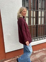Polera de tejido de punto con diseño de ochos, color bordó, de corte oversize y cuello alto, con puños y ruedo acanalados.