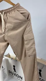 Pantalón cargo de nylon color tostado, corte baggy, con cintura elástica ajustable con cordón y bolsillos laterales con solapa.