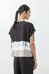 Blusa gris con estampado tie dye, de manga corta y cuello redondo con botones.
