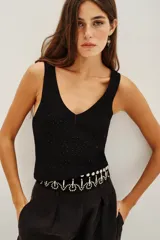 Musculosa de punto color negro con escote en V y detalle de pequeñas aplicaciones brillantes en toda la prenda.