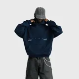 Hoodie de corte oversize color azul marino, con capucha y bolsillo frontal tipo canguro. Presenta un estampado minimalista en el pecho con texto en color blanco.