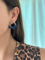 Aro tipo argolla plateado con dije de cuentas de vidrio facetadas en tonos de azul oscuro y cobalto, sujetas con alambre fino plateado.