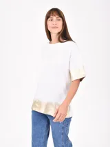 Remera blanca de corte holgado con mangas cortas y detalle plateado en ruedo y mangas.