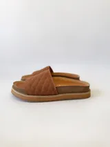 Sandalias chatas color camel, con diseño capitoneado en la tira superior. Fabricadas en cuero.