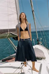 Bermuda ancha de tiro alto, confeccionada en denim color azul, con pinzas delanteras y detalles de vivos a contraste. Cuenta con cierre frontal con cremallera y botón.