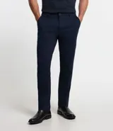 Pantalón de vestir para hombre, color beige claro, de corte slim y sastrería. Presenta cierre frontal con botón y cremallera, y bolsillos laterales y traseros.