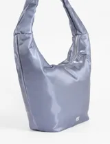 Bolso tipo hobo de color negro con acabado satinado y estructura blanda. Cuenta con un asa corta integrada, cierre superior y un llavero decorativo con temática de tenis colgando del tirador del cierre.