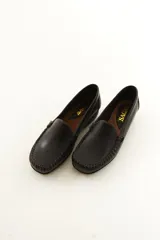 Mocasines de cuero vacuno color beige con acabado mate, costuras visibles artesanales en el empeine y suela de perfil bajo.