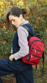 Mochila rosa de tafeta con apertura superior con cierre y tiradores metálicos, bolsillos internos, bolsillo con doble cierre metálico al frente, asas rígidas de mano y correas regulables para colgar en la espalda.