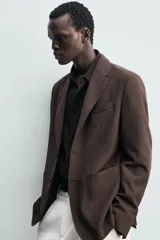 Blazer de corte regular fit confeccionado en tejido de lana, con cuello de solapas de muesca, manga larga con puños abotonados, bolsillos de vivo en el pecho y de plastrón en la cadera, cierre frontal de un botón y aberturas en la espalda.
