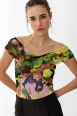 Top de tul estampado con diseño cruzado en el frente y escote tipo bote que deja los hombros al descubierto. Presenta un patrón abstracto en tonos verdes, amarillos, rosados y negros.