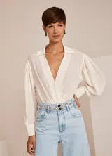 Body color crudo con cuello solapa, escote en V, manga larga con botones en los puños y detalles fruncidos.