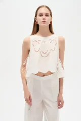 Musculosa de algodón color celeste, con cuello redondo y detalles bordados en tono blanco con diseño de broderie en la parte frontal. Cuenta con cordones laterales para ajustar.