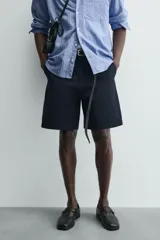 Bermuda de hombre color azul marino, de corte relajado (relaxed fit), confeccionada en tejido con textura. Presenta bolsillos frontales y bolsillos traseros de vivo, con cierre frontal de cremallera y botón.