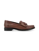 Mocasín de cuero color marrón cognac con detalle de flecos y borlas en el empeine, costuras pespunteadas y suela plana con pequeño tacón.