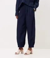 Pantalón de poliamida color azul marino, con diseño barrel de piernas anchas, cintura estructurada con pasacintos y pinzas frontales. Cuenta con botamanga levemente ajustada.