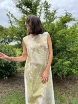 Vestido midi de corte evasé con estampado de hojas en tonos verdes y beige.