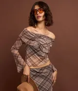 Blusa de tule con estampado de cuadros, escote hombro a hombro, mangas largas acampanadas y canesú fruncido.