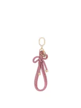 Llavero con correa de muñeca en color rosado, completamente revestido con cristales brillantes, atado en forma de nudo y con herrajes metálicos dorados.