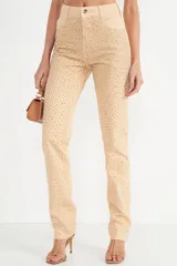 Pantalón de jean color beige con apliques de strass dorados.