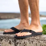 Sandalias tipo ojota para hombre, color negro, con tiras de tela resistente y suela acolchada diseñada para mayor confort.