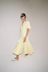 Vestido largo de Zara Woman Collection color amarillo claro, confeccionado en mezcla de algodón. Cuenta con escote en V, manga corta, corte en la cintura y falda evasé con pliegues marcados.