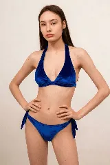 Conjunto de bikini azul de tela aterciopelada, compuesto por un corpiño estilo halter con copas triangulares y una bombacha con tiras laterales para anudar.