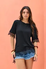 Remera negra de corte asimétrico, con mangas cortas y detalles de encaje en el dobladillo y las mangas.