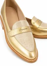 Mocasines de cuero plateado con acabado texturado, diseño clásico con costuras visibles y vira de suela natural cosida. Cuenta con taco plano de 2 cm y plantilla anatómica.