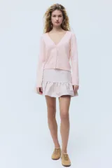 Cardigan de punto suave color rosado, con escote en V, cierre frontal de botones y puños y dobladillo acanalados.