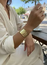 Brazalete ancho de bronce con textura martillada o rugosa, de diseño abierto y ajustable.