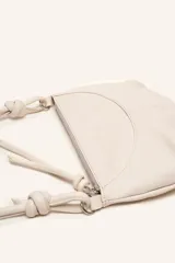 Cartera bandolera de cuero marrón con forma relajada, diseño de costuras curvas y detalles de nudos hechos a mano en las asas.