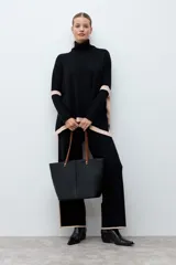 Polera de tejido de punto con cuello alto, diseño holgado y detalles en color contraste en los laterales y ruedo.