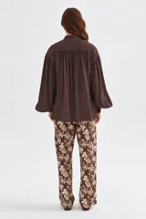 Blusa de lyocell color marrón, con diseño holgado, escote en V con cordón para atar y mangas largas abullonadas con puños ajustados.