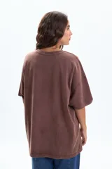 Remera oversize de manga corta color marrón con efecto desgastado y estampado frontal en rosa de hojas y la palabra "BROOKLYN".